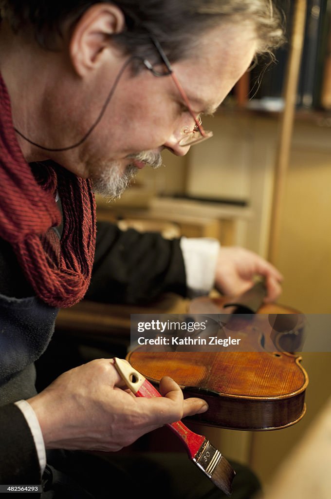 Violin maker varnishing an old instrument