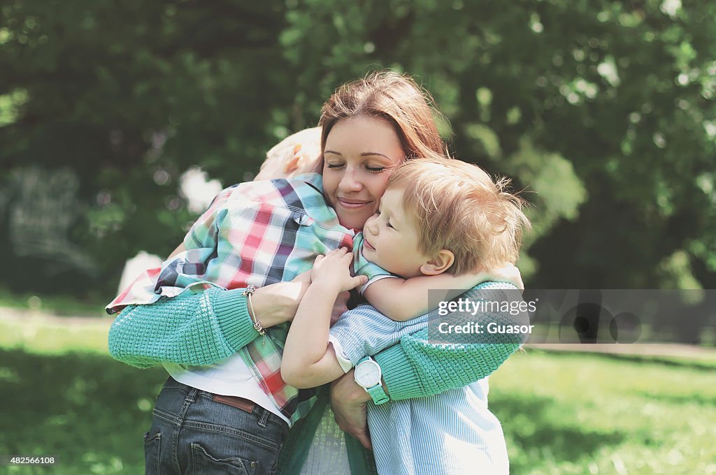 Family happiness! Happy mother tenderly embracing his two sons i