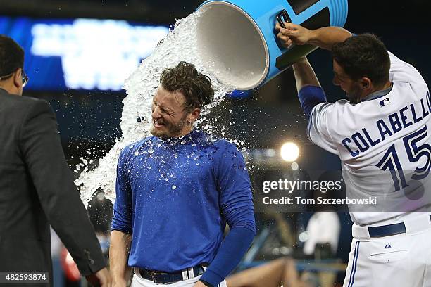 Josh Donaldson of the Toronto Blue Jays is doused with water by Chris Colabello after his game-winning RBI single in the eleventh inning during MLB...