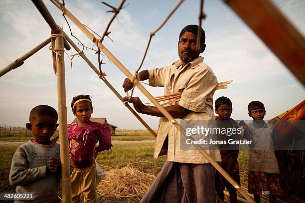 Rohingya man builds the structure of the roof for his bamboo hut in the IDP refugee camp of Sittwe. Sittwe now has over 125,000 people who are...