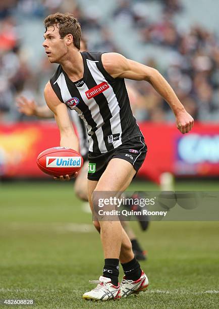 Matt Scharenberg of the Magpies handballs during the round 18 AFL match between the Collingwood Magpies and the Melbourne Demons at Melbourne Cricket...