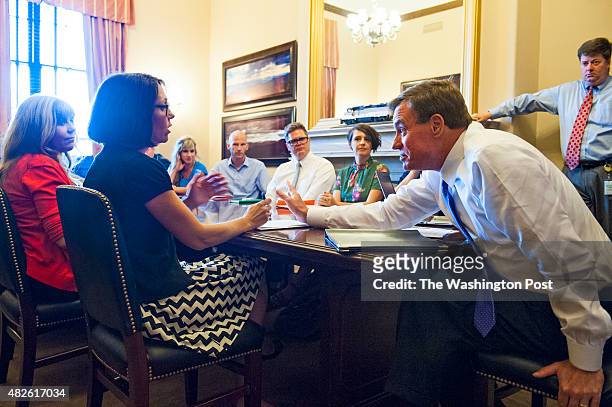 Sen. Mark Warner makes a point while talk with Etsy Global Policy Director Althea Erickson, second from left, during a meeting along with vendors...