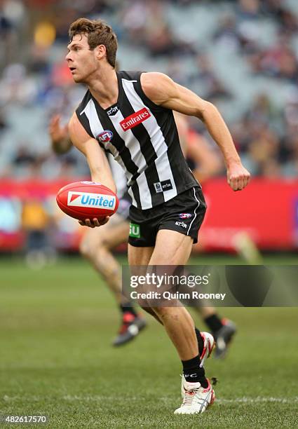 Matt Scharenberg of the Magpies handballs during the round 18 AFL match between the Collingwood Magpies and the Melbourne Demons at Melbourne Cricket...