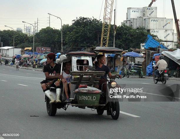 Tricycle carries its passengers and a basket of fish along a bridge in Navotas City, north of Manila, Philippines.
