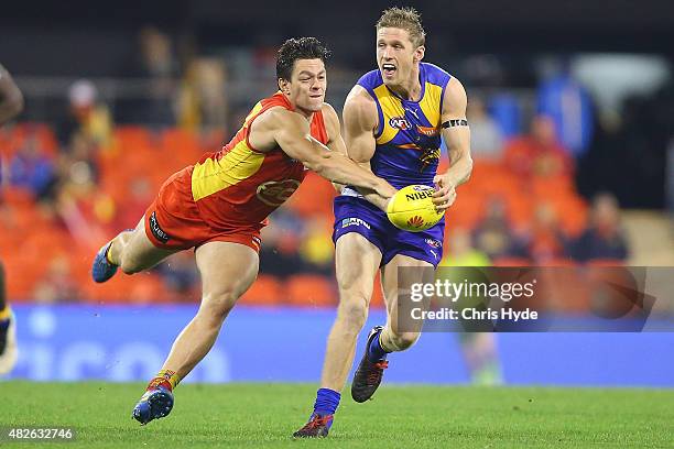 Scott Selwood of the Eagles runs the ball from Jesse Lonergan of the Suns during the round 18 AFL match between the Gold Coast Suns and the West...