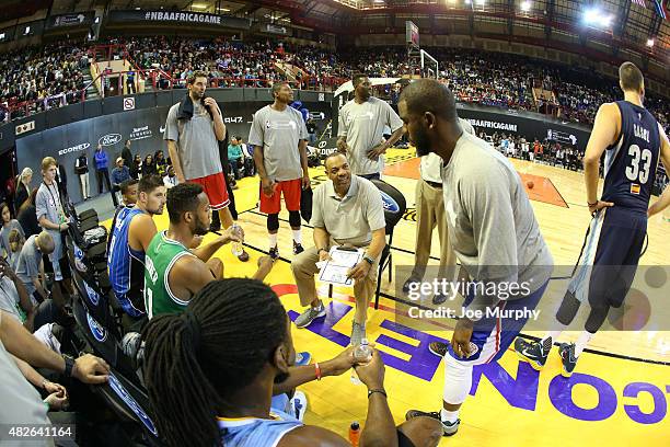 Head Coach Lionel Hollins of Team World goes over the game plan with Chris Paul against Team Africa during the NBA Africa Game 2015 as part of...