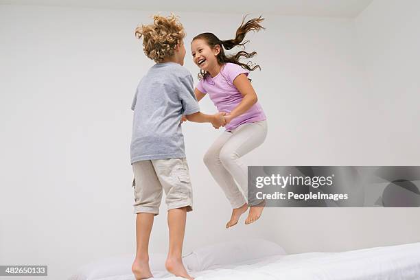 gleeful giggles. - a boy jumping on a bed fotografías e imágenes de stock