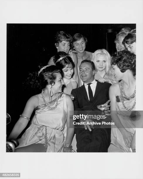 Actor Jack Lemmon smoking a cigarette and drinking champagne whilst surrounded by women in ancient Greek costume, at the premiere of the movie...