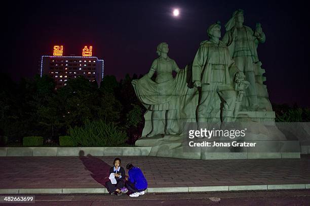 Students sit in the glare of the spotlights shining on the war monuments, many North Korean students in Pyongyang come here to study during the night...