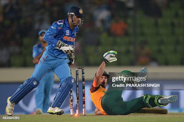 India wicketkeeper captain Mahendra Singh Dhoni celebrates as South African batsman captain Faf du Plessis falls to the ground after being clean...