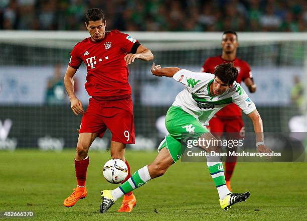 Robert Lewandowski of Bayern Muenchen battles for the ball with Timm Klose of VfL Wolfsburg during the DFL Supercup match between VfL Wolfsburg and...