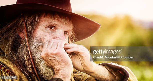 close-up of a mature cowboy playing the harmonica - harmonica stock pictures, royalty-free photos & images
