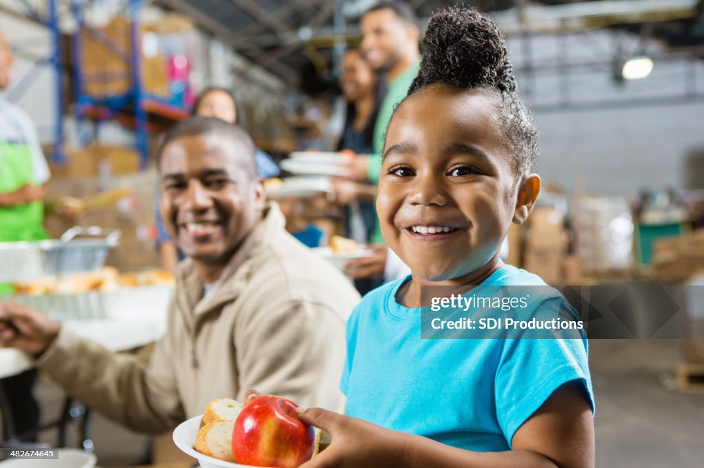 Jeune fille avec le Père manger de la nourriture saine à Soupe populaire