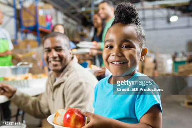 young girl with father eating healthy food at soup kitchen - childhood hunger stock pictures, royalty-free photos & images