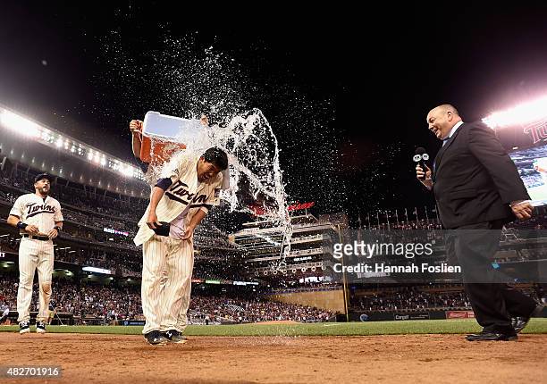 Brian Dozier of the Minnesota Twins pours wate on teammate Kurt Suzuki as Trevor Plouffe and Kevin Gorg of Fox Sports North look on after a walk-off...