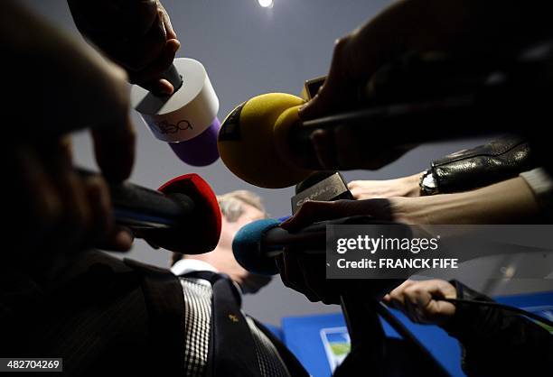 Journalists hold up microphones as French Ligue de Football Professionnel President Frederic Thiriez speaks during a press conference on April 4,...