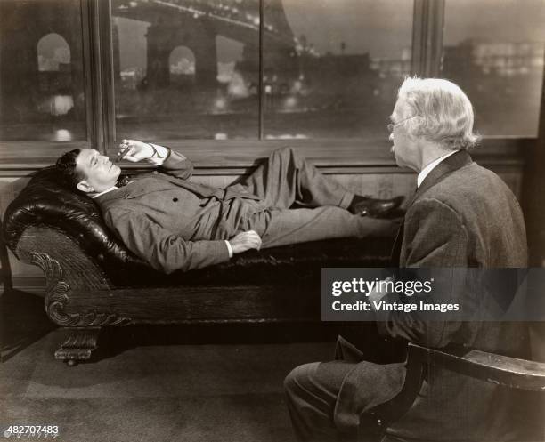 American actor Richard Dix as private detective Don Gale, reclining against a New York City backdrop in a scene from the Columbia Pictures film...