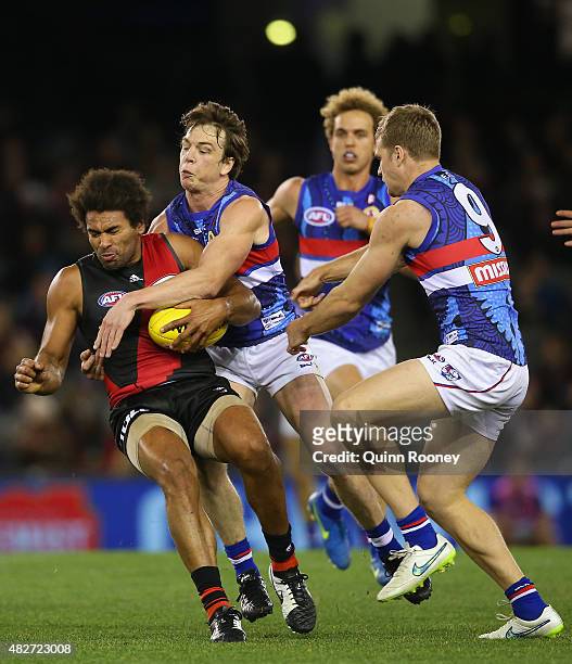 James Gwilt of the Bombers is tackled by Liam Picken of the Bulldogs during the round 18 AFL match between the Essendon Bombers and the Western...