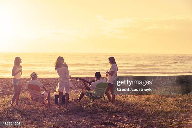 relaxed friends beach party at sunset - couple sand sunset stock pictures, royalty-free photos & images