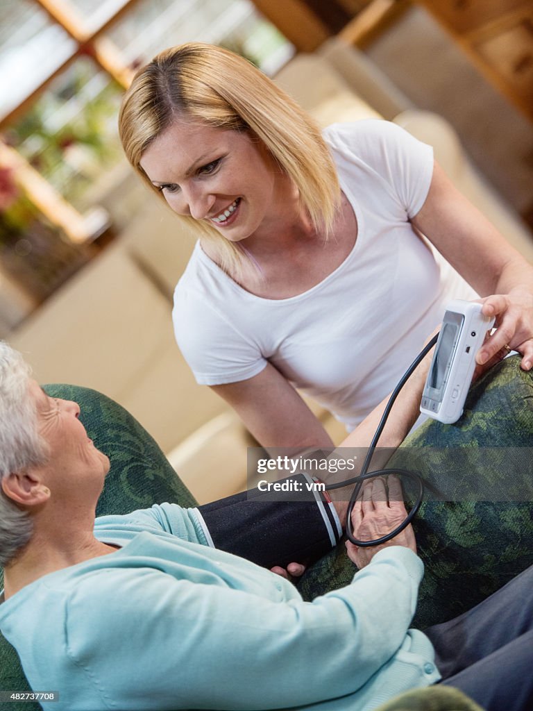 Enfermera de comprobación de la presión arterial de una mujer mayor