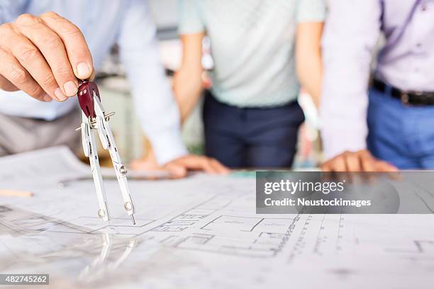 engineers measuring blueprint with drawing compass at desk - employee engagement survey stock pictures, royalty-free photos & images