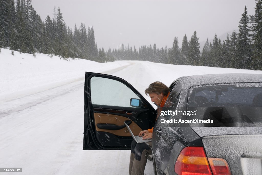 Homem usando computador para contatar ajuda na tempestade de neve