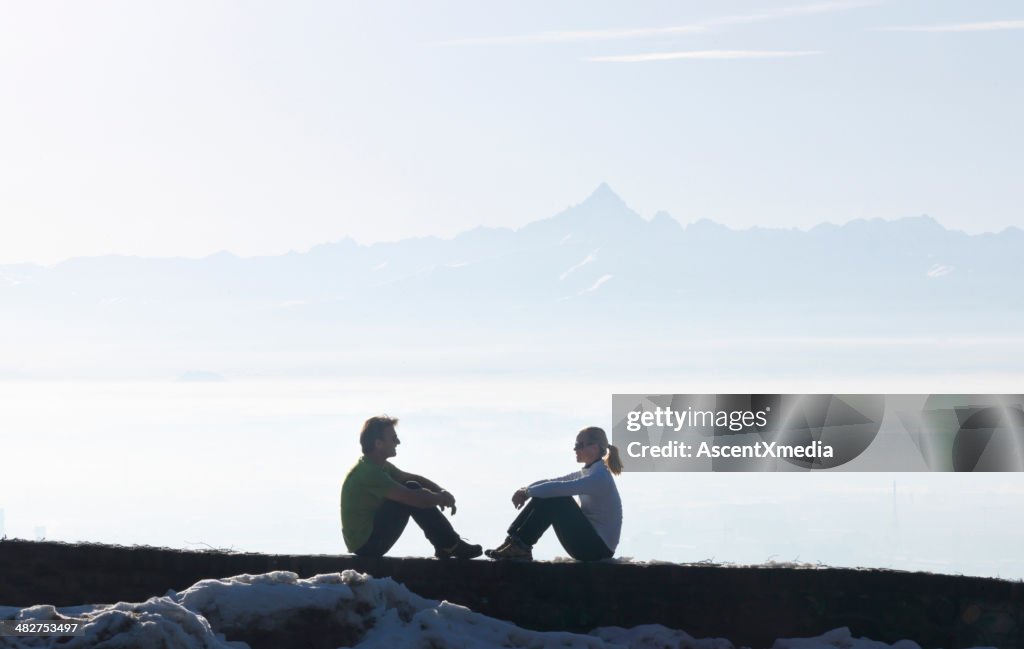 Couple sitting on bluff above mountains