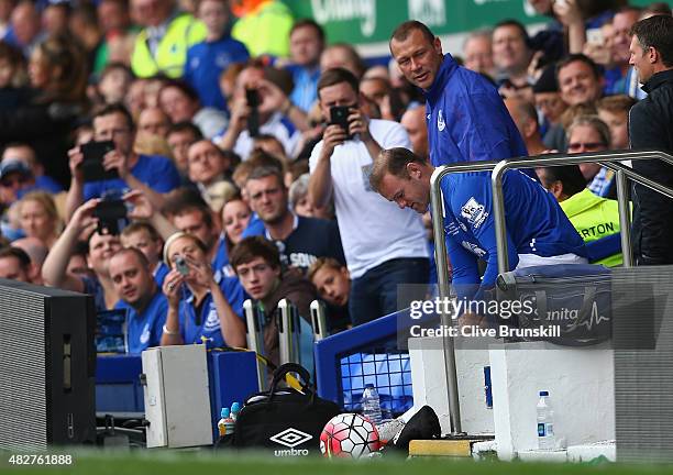 Wayne Rooney of Everton and Manchester United is watched closely by Duncan Ferguson before running on to the pitch to replace Tom Cleverley of...