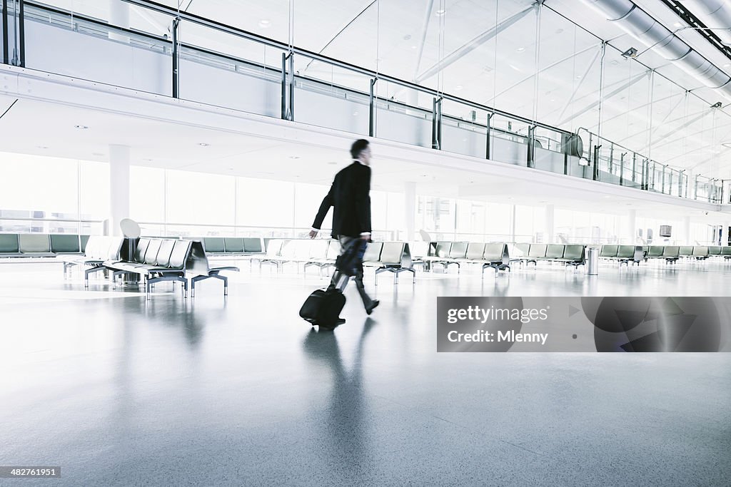 Hombre de negocios en traje de paseos en terminal de aeropuerto