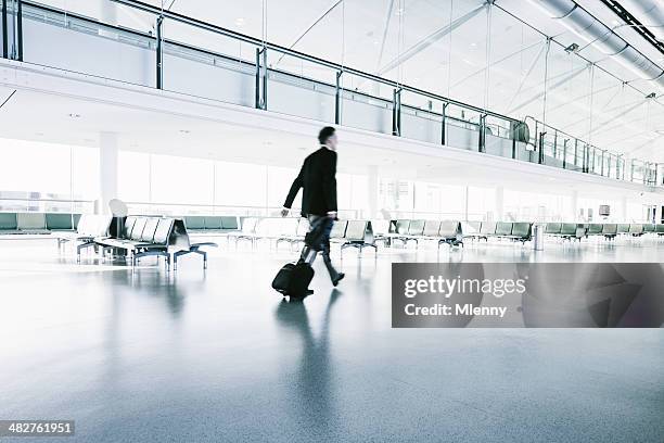 businessman in a suit walks in airport terminal - heathrow stock pictures, royalty-free photos & images