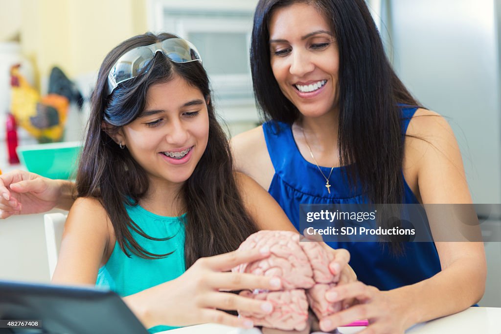 Mature mother teaching her preteen daughter during homeschool science class