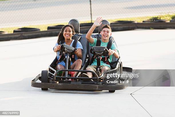 teenage couple riding go carts at amusement park - go carting stock pictures, royalty-free photos & images