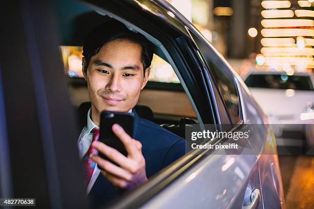 japanese businessman in a car at the night - smartphone car stock pictures, royalty-free photos & images