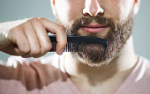 Unrecognizable man combing his beard