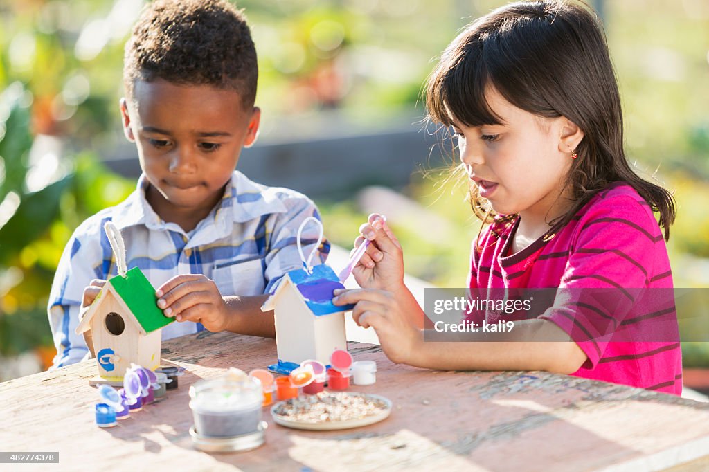 Multi-ethnic children painting little wooden bird houses