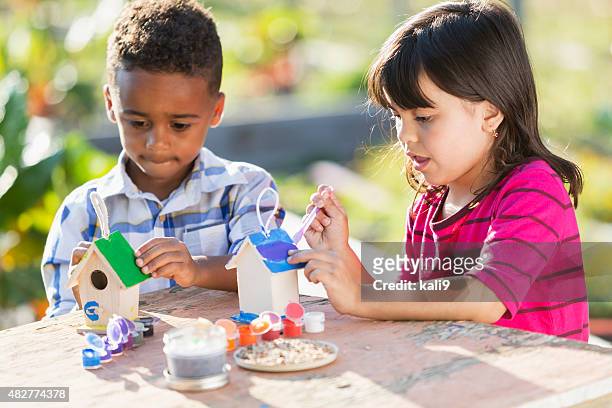 multi-ethnic children painting little wooden bird houses - birdhouse stock pictures, royalty-free photos & images