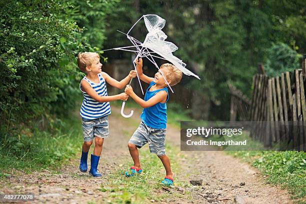 umbrella malfunction - two boys with broken umbrella - broken umbrella stockfoto's en -beelden