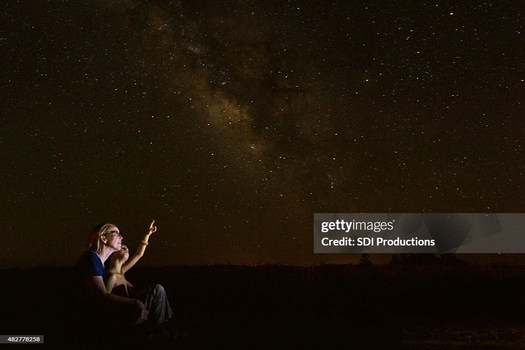 Mother star gazing with young son while he studies constellations