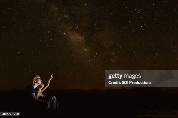 mother star gazing with young son while he studies constellations - family night stock pictures, royalty-free photos & images