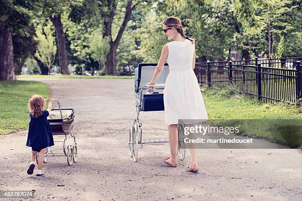 mother and daughter walking babies in vintage prams. - fashionable mom stock pictures, royalty-free photos & images