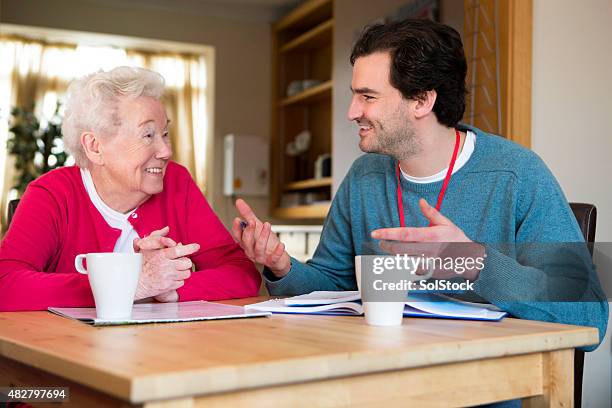 friendly male volunteer assisting a senior woman with paperwork. - male volunteer stockfoto's en -beelden