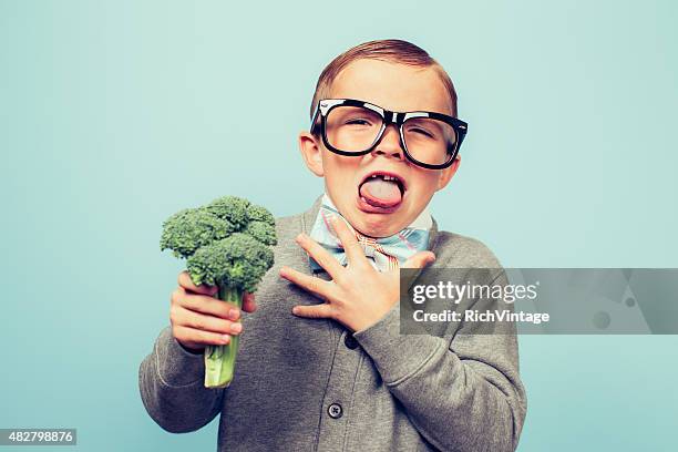 nerd hates joven niño comiendo broccoli - disgust fotografías e imágenes de stock