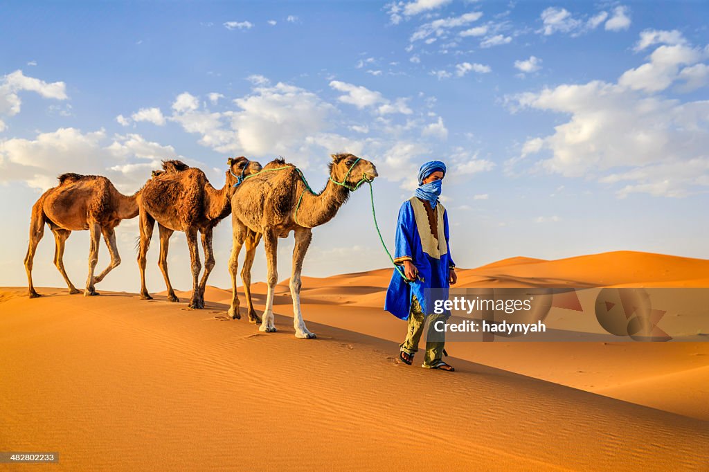 Giovane Tuareg con cammelli nel deserto del Sahara occidentale dell'Africa