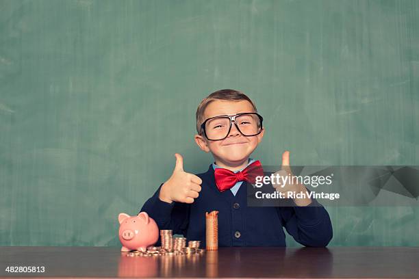 young boy nerd ahorra dinero en la alcancía - kids money fotografías e imágenes de stock