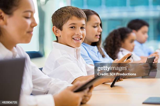 happy hispanic boy using technology in private school classroom - school uniform stock pictures, royalty-free photos & images