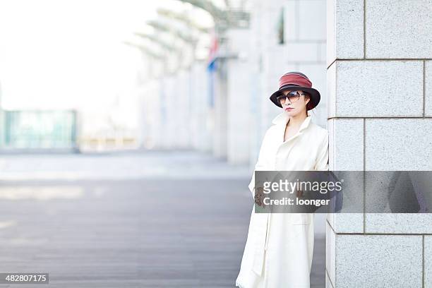 woman leaning on a shopping mall column - overcoat stock pictures, royalty-free photos & images