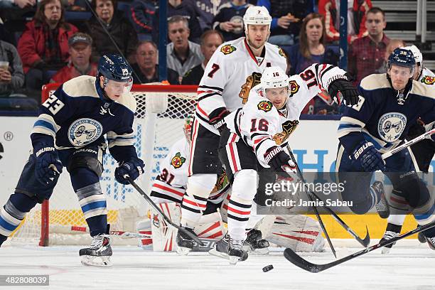 Matt Frattin of the Columbus Blue Jackets and Marcus Kruger of the Chicago Blackhawks reach for a loose puck during the second period on April 4,...