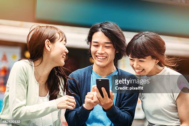 グループの若い日本人に、スマートフォン - asian outdoor ストックフォトと画像