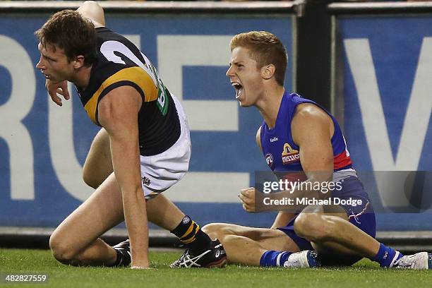 Lachie Hunter of the Bulldogs celebrates a goal next to Dylan Grimes of the Tigers during the round three AFL match between the Western Bulldogs and...