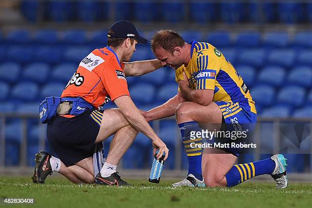 David Gower of the Eels receives attention from trainer Paul Devlin on the field during the round 21 NRL match between the Gold Coast Titans and the...